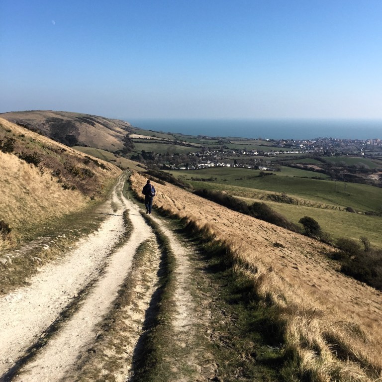 A walker on the Purbeck Way with Swanage in the distance