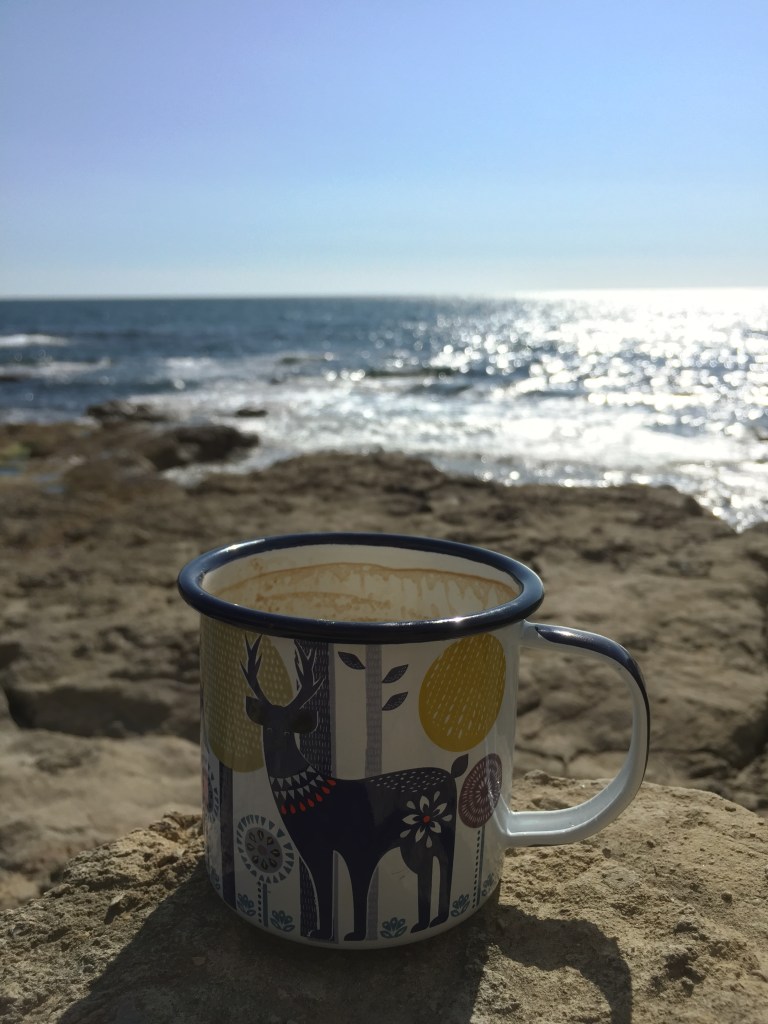 A painted enamel mug resting on the rocks at Winspit, near Worth Matravers in Dorset, UK