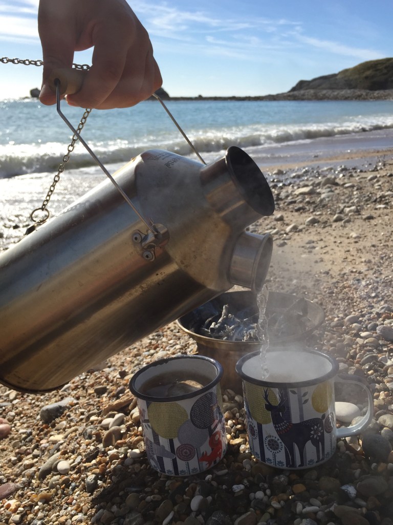 Making tea with a Kelly Kettle on the beach at Mupe Bay, between Worbarrow Bay and Lulworth Cove, on the Jurassic Coast, Dorset, UK